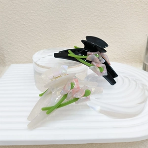 Detailed view of acetate flower hair claws in classic black and pearlized cream white