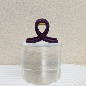 Détail de la pince à cheveux croisée violet foncé avec ressort en métal doré brillant