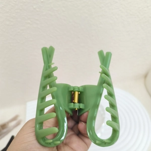 Close-up of grass green PVC hair claw clip with cross fishbone design and metal spring