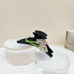 Close-up of elegant black acetate hair claw with pink and white calla lily flower detail