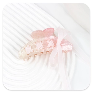 Detail of pink glitter hair claw clip with crossed ribbons and bow accent