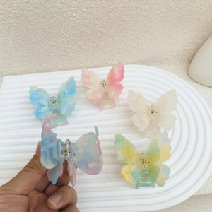 Détail de pinces à cheveux papillon en acrylique coloré montrant le mécanisme à ressort