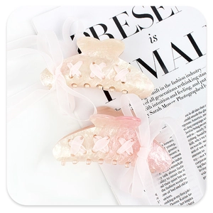 Detailed view of pink acrylic butterfly hair clips with glitter ribbon and mesh accents