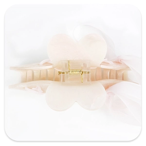Detail of light pink acrylic shark hair clip with shimmer finish and chiffon ribbon