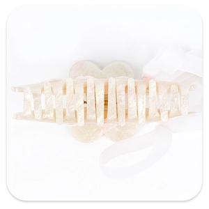 Detail of pearlescent white and pink hair claw with glitter finish and mesh ribbon