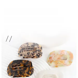 Detailed view of four acetate hair claws in various textures and marble patterns