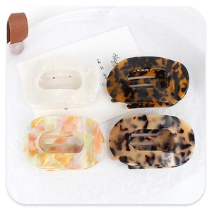 Detailed view of four acetate hair claw clips with marble and tortoiseshell patterns