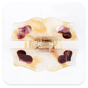 Detail view of acetate heart pattern hair claw with marble texture and gold metal spring