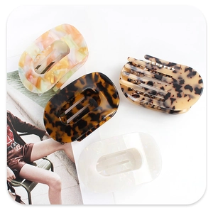 Flat lay of four hollow oval acetate hair claws in tortoise shell and marble patterns