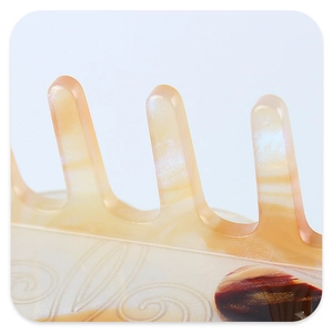 Macro detail of acetate shark clip showing pearlescent marbling and gold powder texture