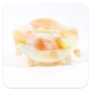 Macro view of curved acetate hair claw clip with colorful marble texture and smooth teeth
