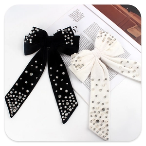 Detail of velvet bow hair clips with pearls and rhinestones on white magazine background