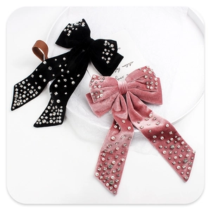 Detail view of velvet bow hair clips with pearls and rhinestones on a white tray