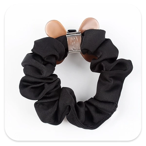Détail d'un chouchou en tissu noir avec un fermoir en métal argenté et des accents d'oreilles