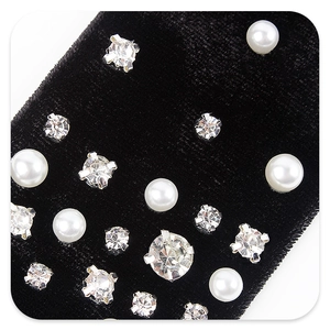 Close-up detail of black velvet bow hair clip with pearls and sparkling rhinestones
