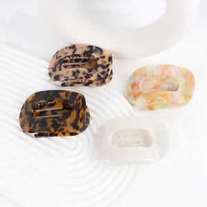 Elegant cellulose acetate hair claw clips in marble and tortoiseshell patterns on white stands