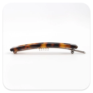 Detail of tortoiseshell acetate hair clip with amber texture and silver metal spring clip