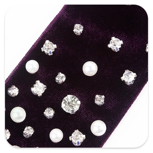 Macro detail of purple velvet hair bow with inlaid pearls and sparkling rhinestones