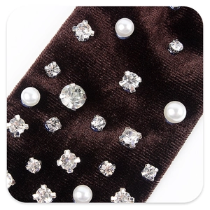 Macro shot of dark brown velvet bow detail with embedded rhinestones and pearls