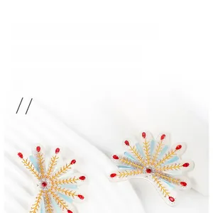 Détail de barrettes plumes de paon avec strass rouges sur tissu blanc soyeux