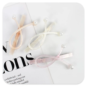 Close-up of acetic acid hair clips with pearls in champagne pink, white, and lilac colors