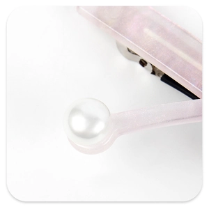 Detail of light pink acetate hair clip with glitter finish and white faux pearl accent