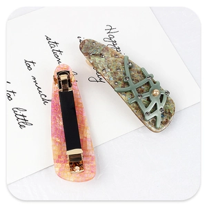 Detail of pink and green branch-shaped acetate hair clips with pearls and rhinestones