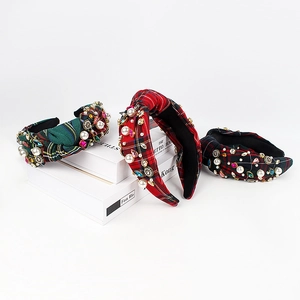 Three plaid padded headbands with sparkling rhinestones and white pearls set on books