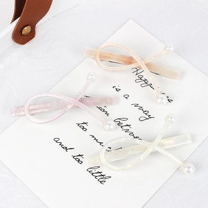 Three acetate hair clips with pearls in loop design featuring iridescent pink and blue tones