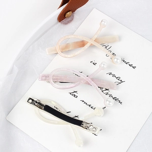 Three-piece acetate hair clips with pearl accents in peach, purple, and cream