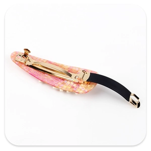 Macro shot of branch shaped hair clip with orange mosaic texture and gold spring metal grip