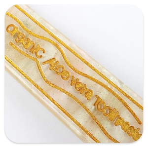 Macro shot of acetic hair clip with golden aloe vera toothpaste text and wavy patterns