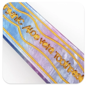 Detail of blue marble acetate hair clip with organic toothpaste text and gold wave