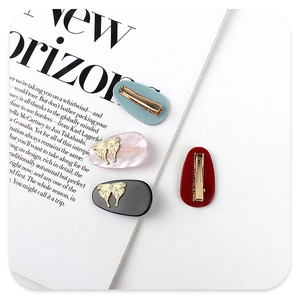 Close-up of vintage marble texture hair clips with golden butterfly accents on a magazine
