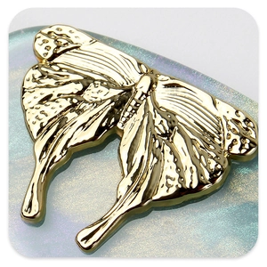 Detailed close-up of golden butterfly hair clip with realistic wings texture and metallic shine