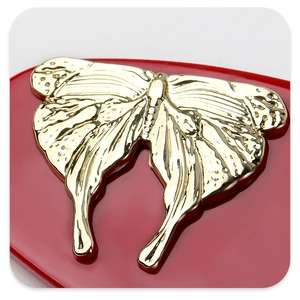 Detailed macro view of a golden metal butterfly hair clip on a red glossy heart base
