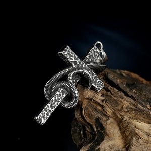 Gothic stainless steel snake cross pendant with vintage hammered texture on dark wood