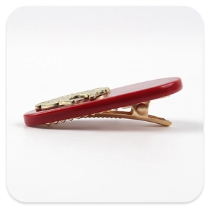 Detail view of the elegant red acetate hair clip with golden metal bear ornament