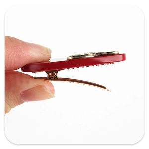Macro view of a red acetate hair clip with gold metal base and embossed ornament