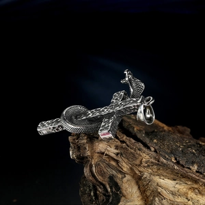 Macro shot of hammered stainless steel cross pendant with detailed cobra snake wrapping