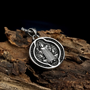 Vintage Saint Benedict medal pendant in aged silver finish on a dark wood texture