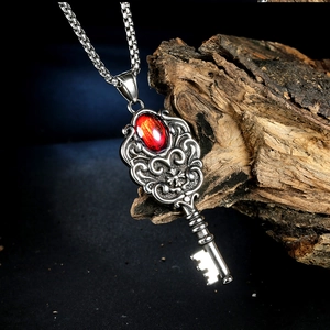 Detailed close-up of retro punk key pendant with red gemstone on a dark wood background