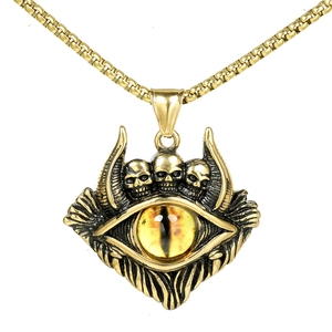 Close-up of gothic skull pendant with yellow evil eye and golden box chain jewelry