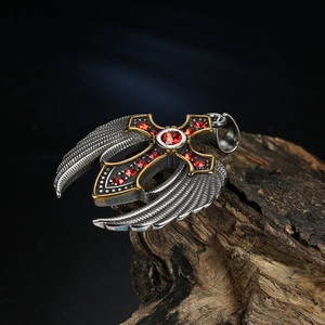 Detail of gothic cross pendant with red rhinestones and silver wings on a wood base
