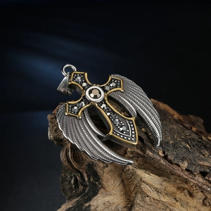 Detail of silver and gold stainless steel cross pendant with wings on wood base