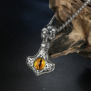 Detalle del colgante Vikingo Mjölnir con calavera y piedra ojo de gato naranja incrustada