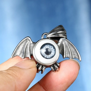 Macro shot of Gothic bat wing pendant with realistic blue eye detail held in hand