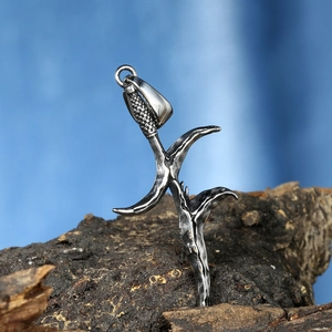 Detailed view of punk dagger pendant with aged silver finish on dark tree bark base
