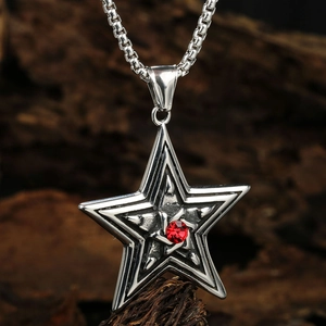 Star-shaped necklace with a red center stone on a wooden background