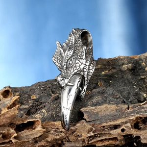 Detailed dragon head pendant on aged wood with a silver hook in punk style jewelry